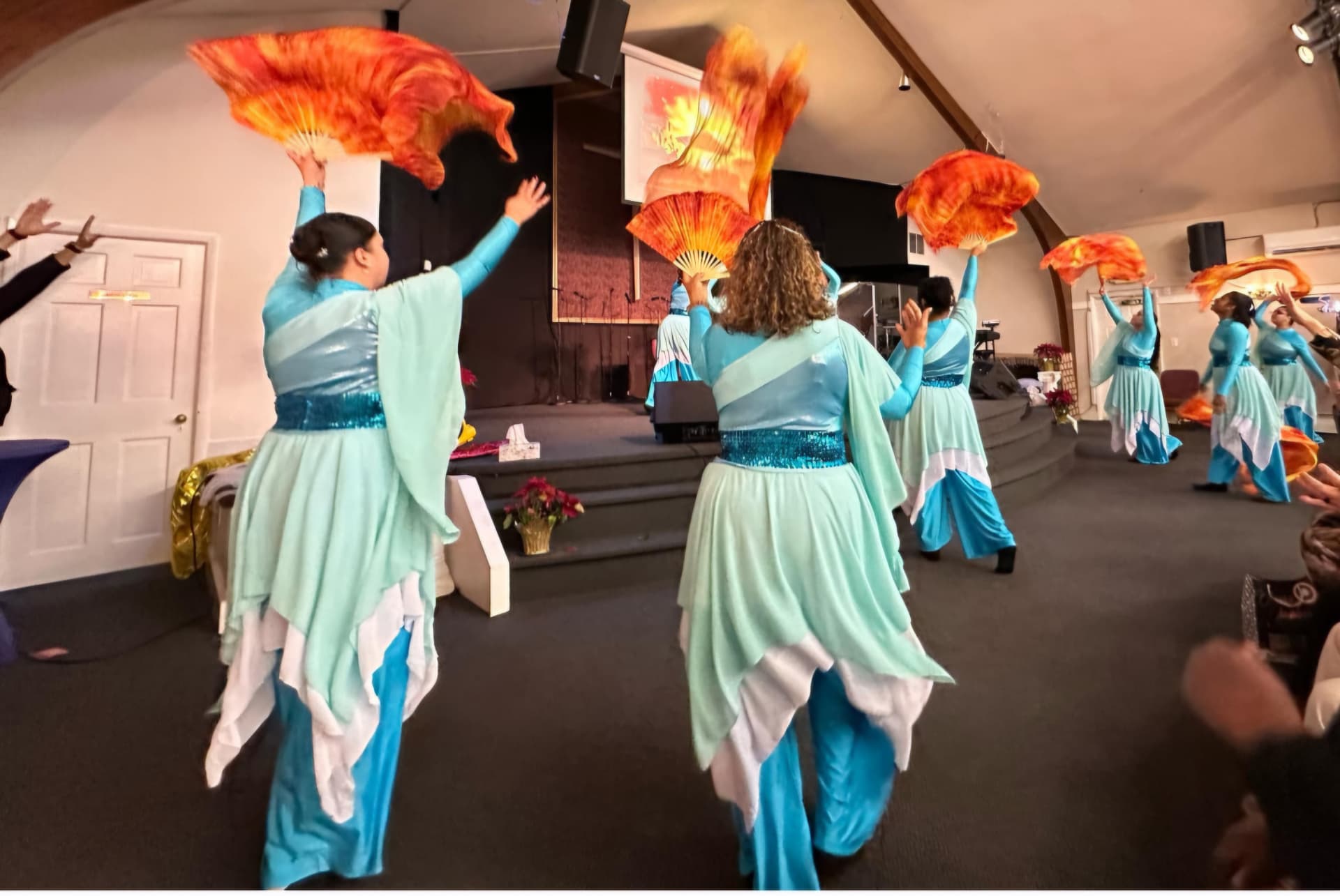 Worship team ministering with flame-colored fan flags during a church service