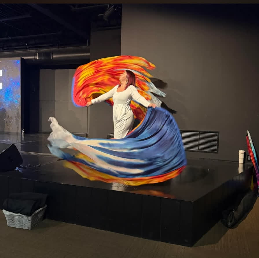 Worshipper dancing with a large fire-and-water silk on stage