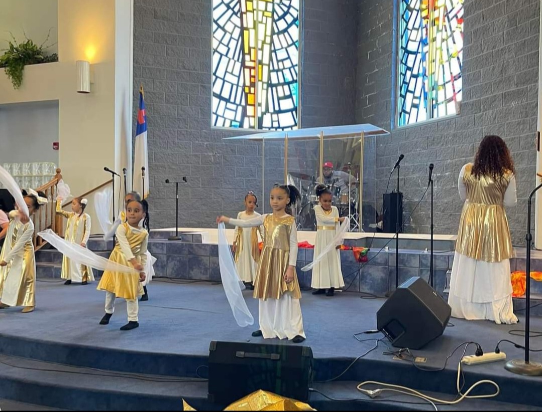 Young worshippers ministering with silks in gold and white during a church service