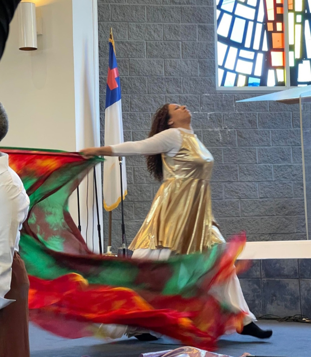 Talina Richardson, Founder & Instructor — lifting flags before a cross in worship