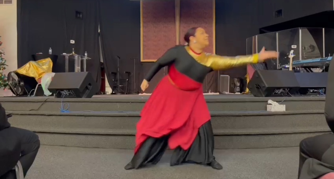 Worshipper in red and black garments ministering in praise dance