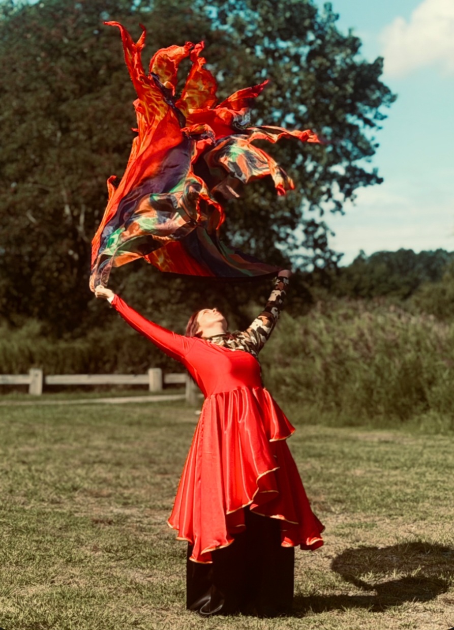 Elba McBride, Educator & Author — raising a red silk flag toward the sky in worship