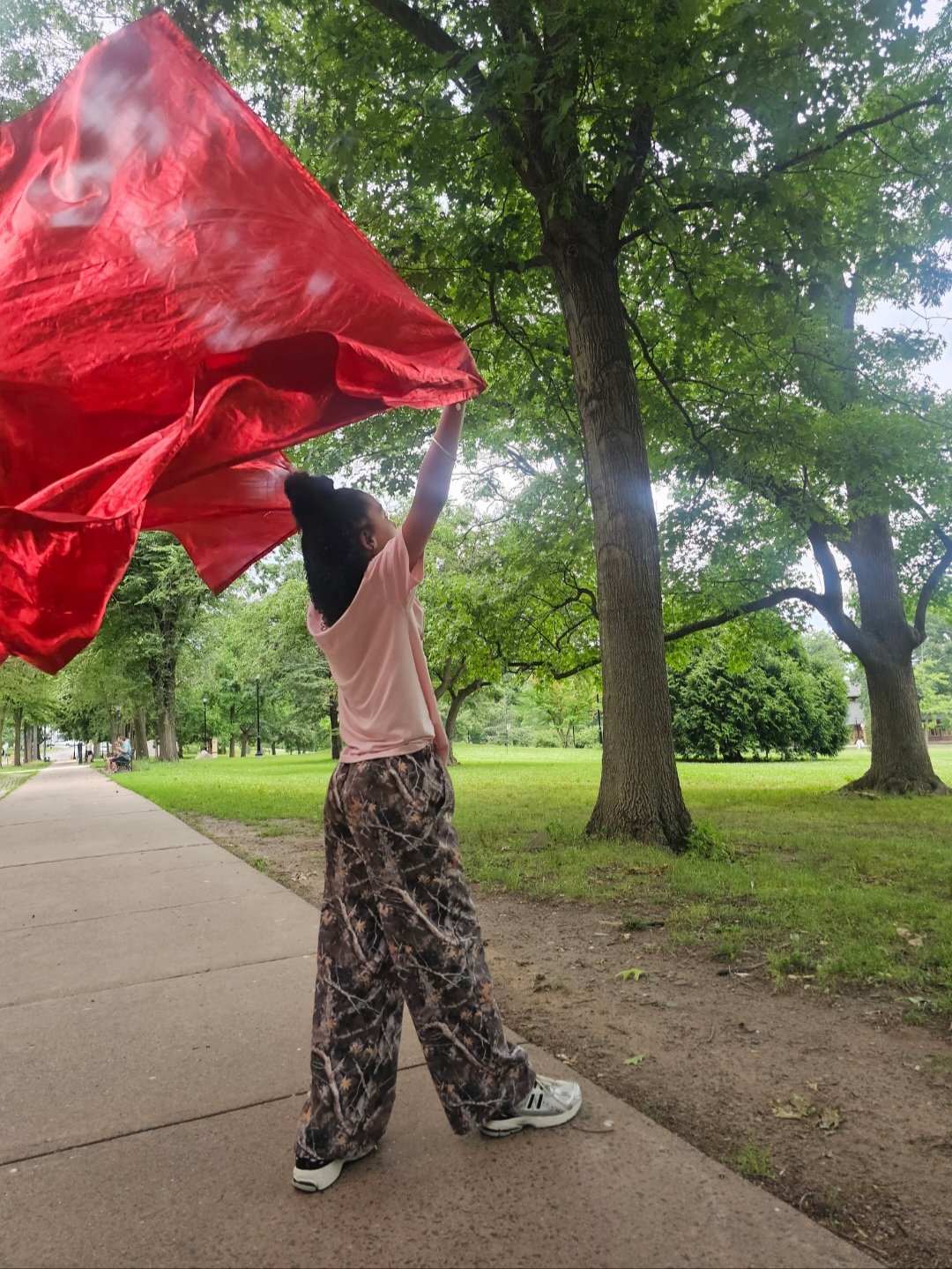 Young worshipper raising a red flag along a park pathway