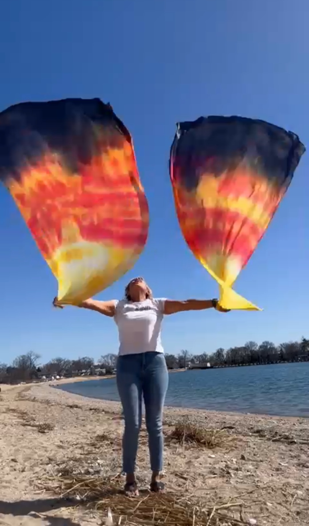 Worshipper lifting fire-colored wing flags on the shoreline