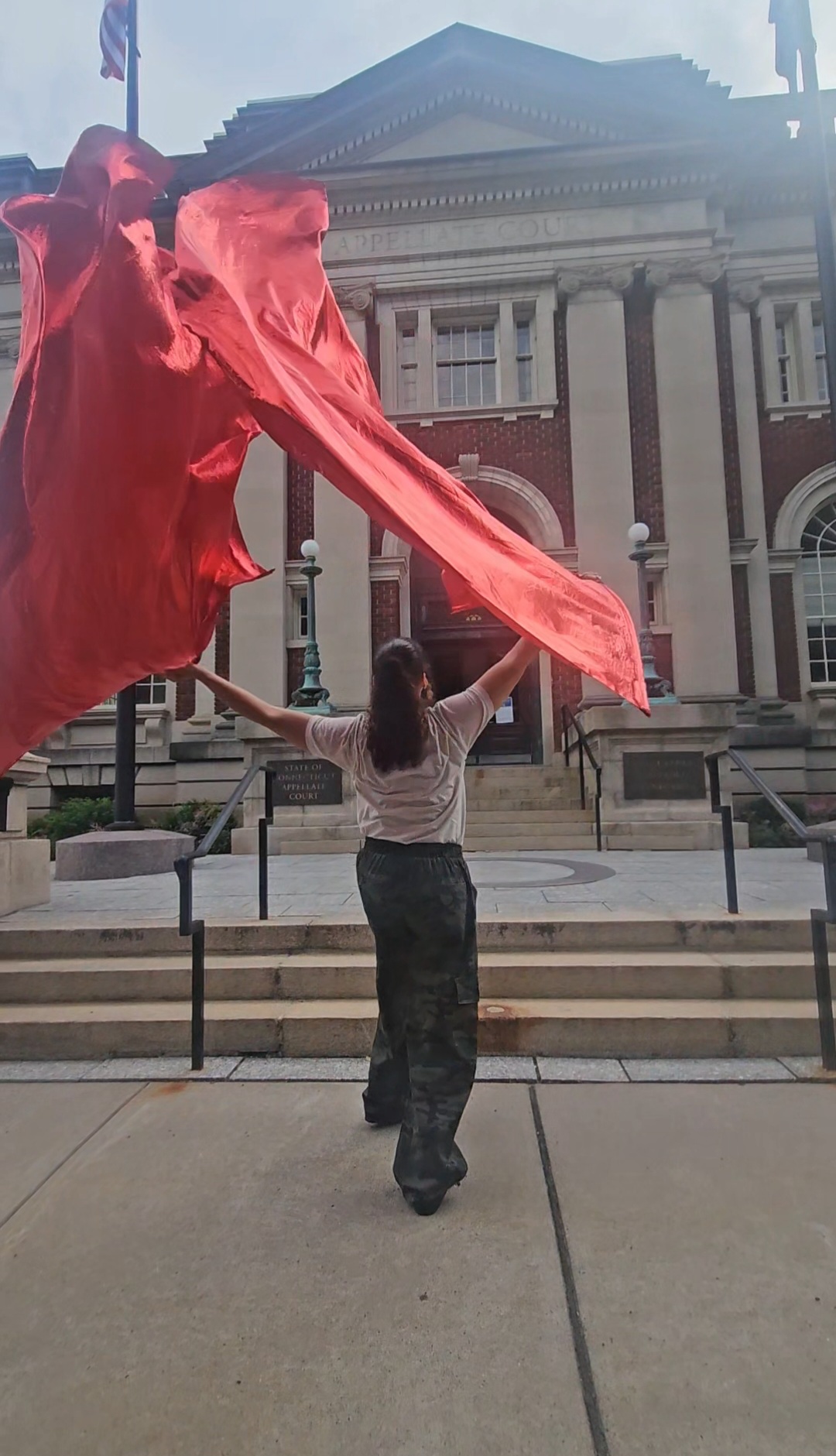 Worshipper lifting a large red silk in prayer before a courthouse