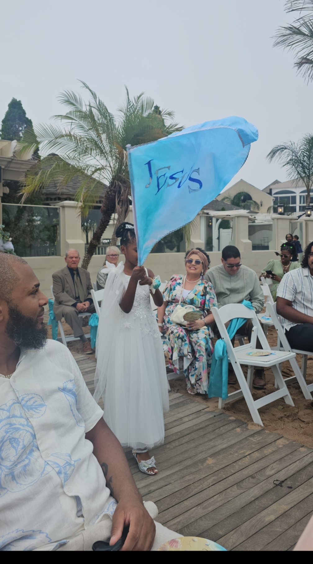 Young girl waving a 'Jesus' flag at an outdoor seaside gathering